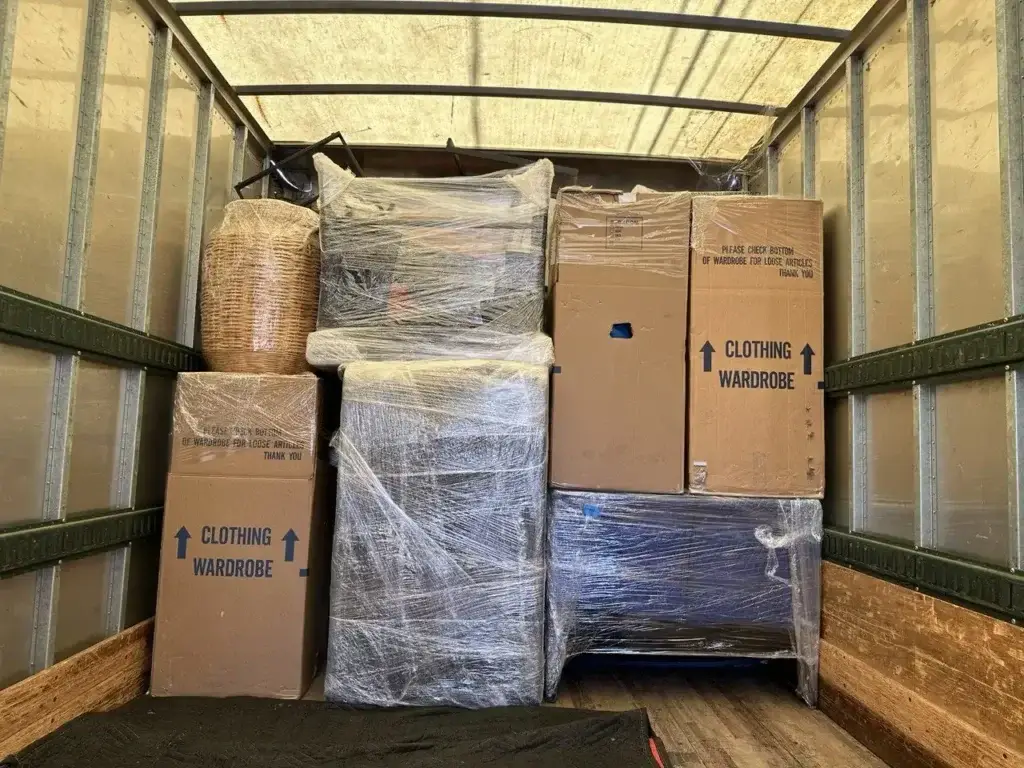 Professional moving truck loaded with wrapped furniture, boxes, and household belongings secured for safe transportation.